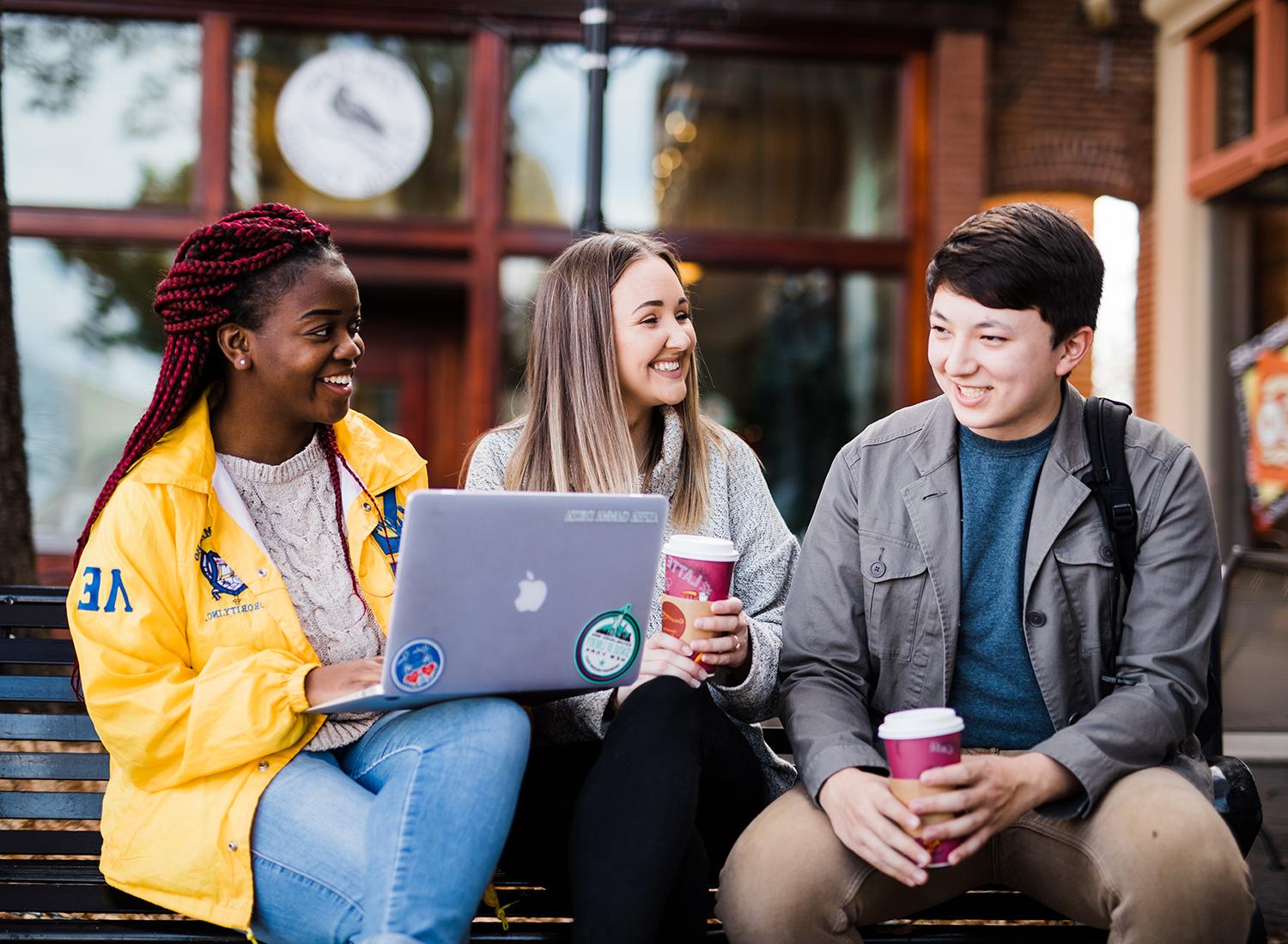 学生们坐在卡罗尔顿广场上边喝咖啡边学习.